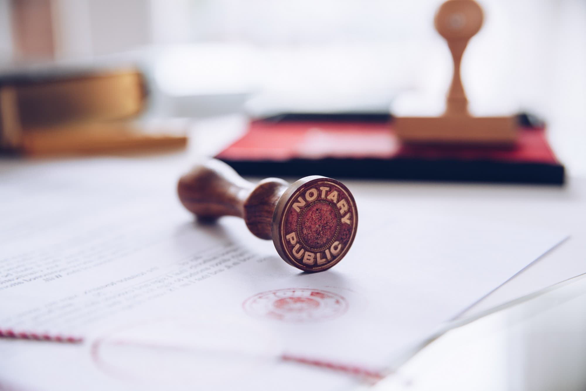 A wooden Notary Public stamp resting on a document beside its red seal impression